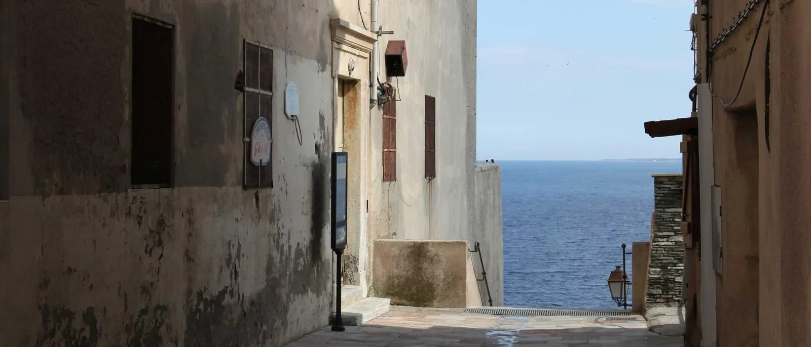 Gasse zwischen hellen Häusern führt zum Meer